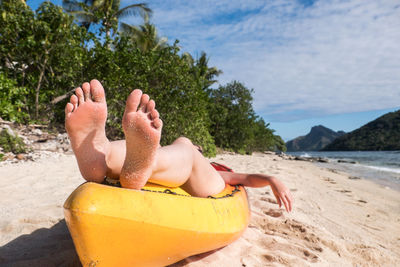 Low section of person in boat at beach against sky