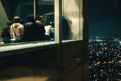 People overlooking illuminated cityscape