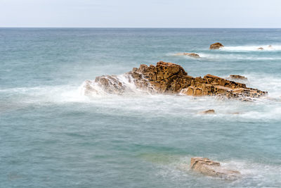 Scenic view of waves splashing against rocks in the pink granite coast, gouffre, brittany, france.