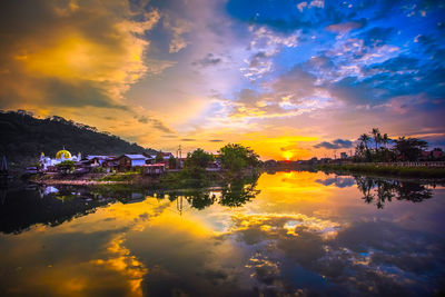 Scenic view of lake against dramatic sky during sunset