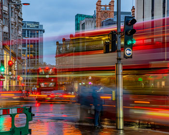 Blurred motion of vehicles on road by buildings in city