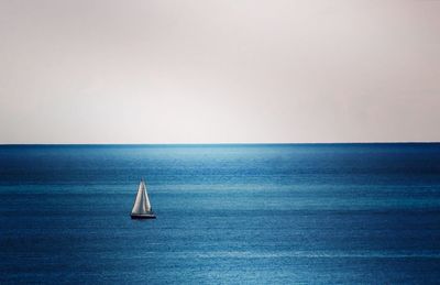 Sailboat sailing in sea against clear sky