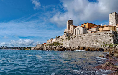 Buildings by sea against sky