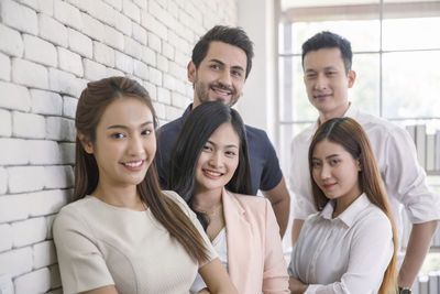 Portrait of smiling friends standing against wall