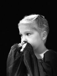 Portrait of boy looking away against black background