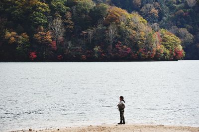 Full length of man standing by sea during autumn