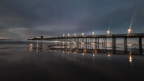 Illuminated bridge over river against sky at night