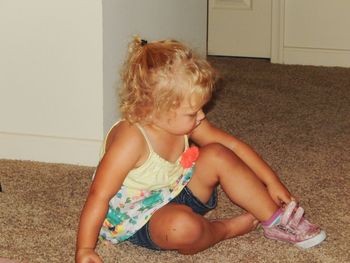 Full length of blond girl wearing shoe at home