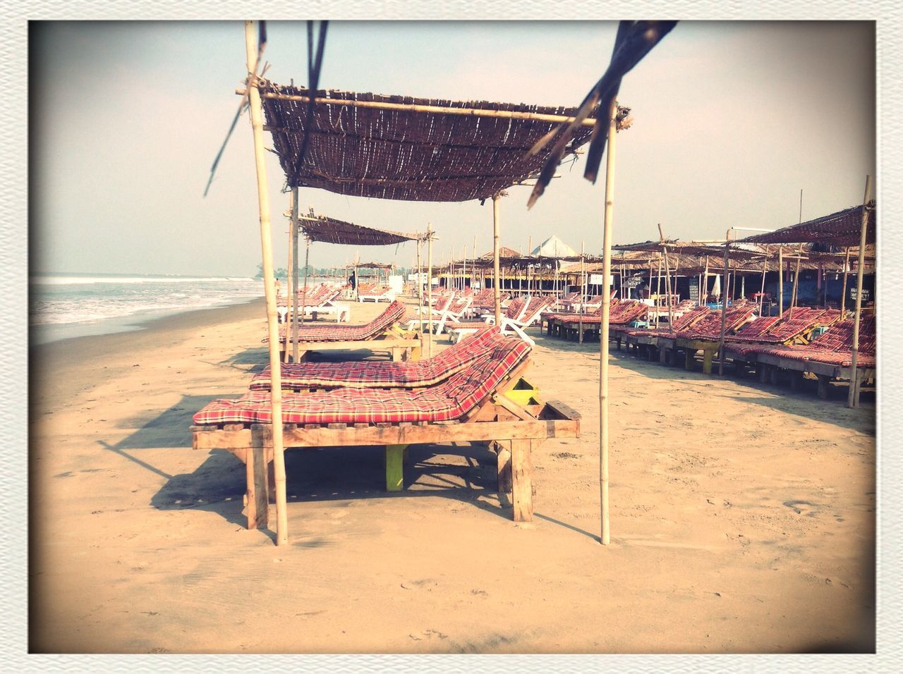 beach, sea, sand, transfer print, shore, horizon over water, water, auto post production filter, sky, beach umbrella, absence, incidental people, clear sky, built structure, sunlight, parasol, lounge chair, chair, day, deck chair