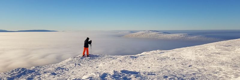 Panoramic view of person on snowcapped mountain against sky