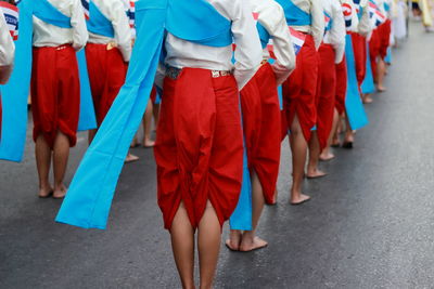 Low section of women in traditional clothing with flags walking on street in city