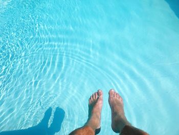 Low section of man relaxing in swimming pool