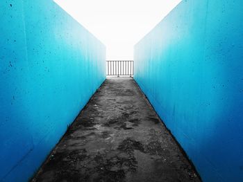 Empty footpath amidst buildings against clear blue sky