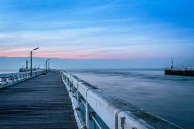 Pier on sea against cloudy sky