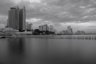 Buildings by river against sky in city