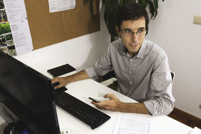 Midsection of man using mobile phone while sitting on table