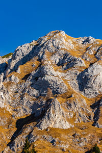 Low angle view of rocks against clear blue sky