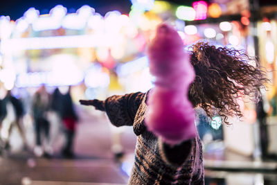 Close-up of woman with illuminated lights in city at night