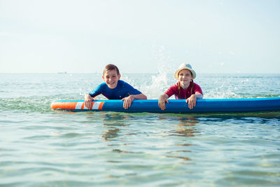 Portrait of friends enjoying in sea against sky