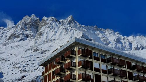 Snow covered houses by mountain against sky