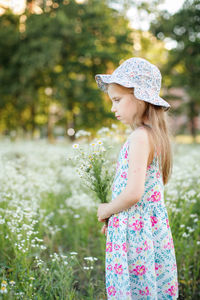 Side view of a girl standing against plants