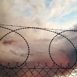Chainlink fence against cloudy sky
