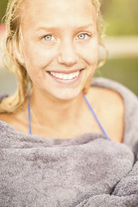 Portrait of smiling young woman wrapped in towel outdoors