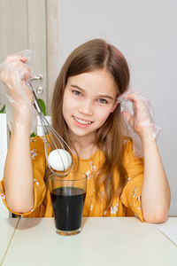 Portrait of cute girl holding egg over paint in glass