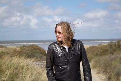 Mid adult man standing on sea shore against sky