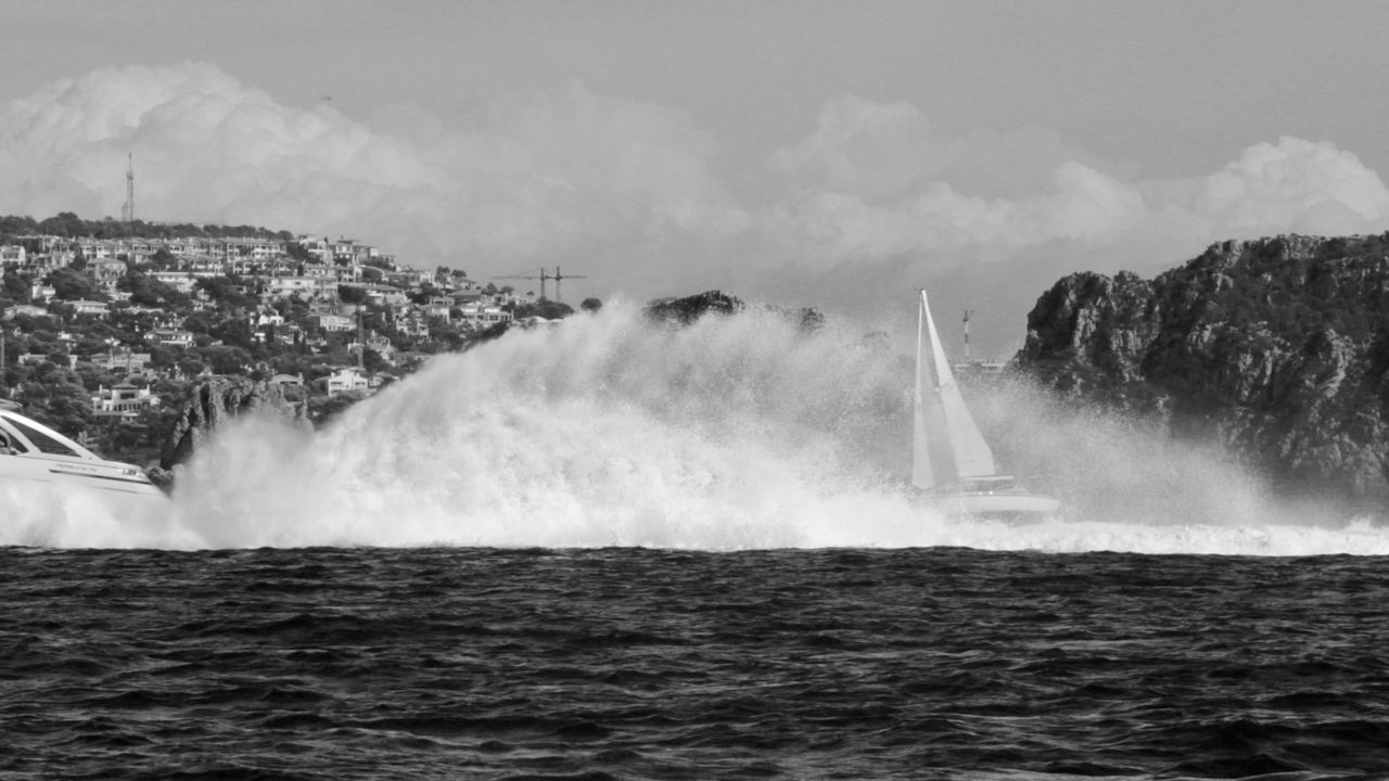 SCENIC VIEW OF WAVES BREAKING AGAINST SEA