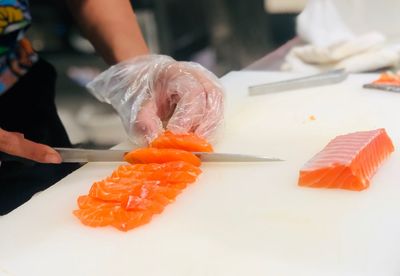 Hand cutting fresh salmon fish,  sashimi 