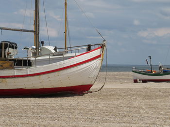 Boats moored at beach against sky