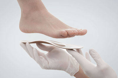 Cropped hand of woman holding seashell against white background