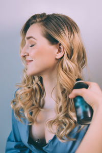 Portrait of smiling young woman against gray background