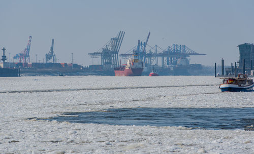 Cranes at harbor against clear sky