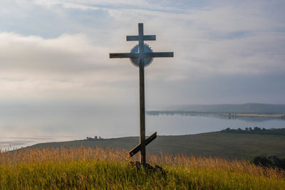 Cross on field against sky