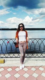 Portrait of beautiful woman leaning on railing against sea