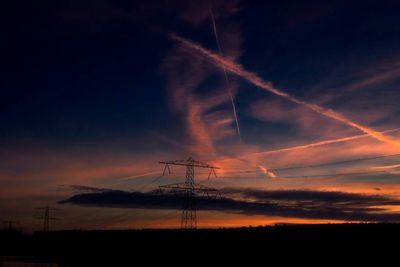 Silhouette of electricity pylon at sunset