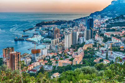 Aerial view of buildings by sea against sky