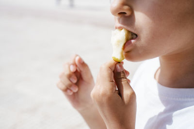 Boy eating pear outdoors