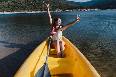 Full length of woman in bikini with dog sitting on boat in lake