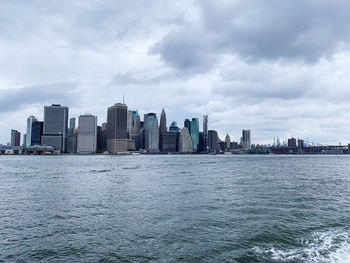 Sea by buildings in downtown new york city against sky