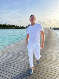 Portrait of young man standing against sea