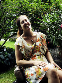 Full length of young woman sitting against plants