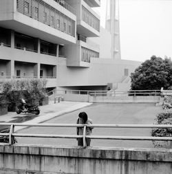 Woman by building in city against sky