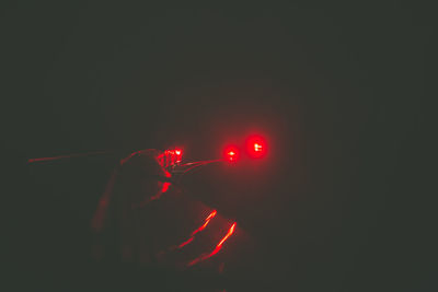 Man holding illuminated lights at night