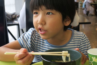 Close-up of boy having noodles while holding chopsticks