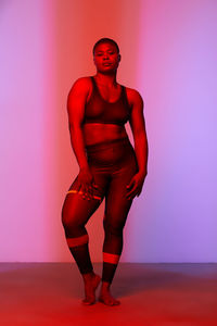 Woman in sports clothing standing against colorful background