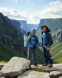 Portrait of male hikers standing against mountains on rocks at gros morne national park