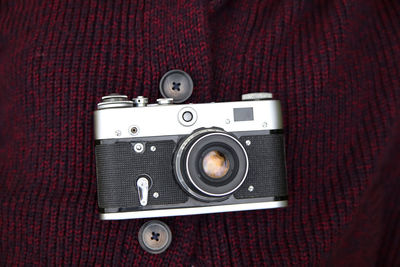 Retro film photo camera on red knitted sweater background. old retro camera on vintage background